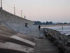 Curved, sloping concrete seawall with rock rip-rap