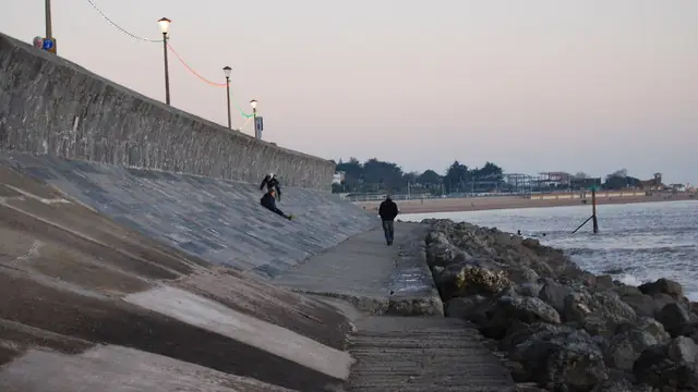 Curved, sloping concrete seawall with rock rip-rap